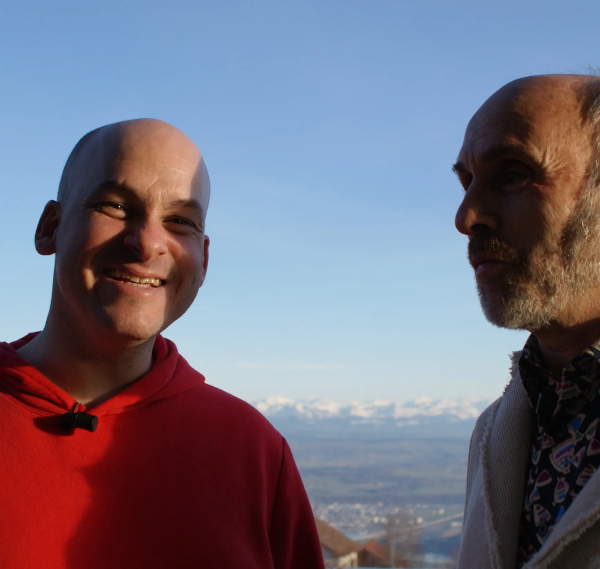 photo d'Alexandre Jollien et Jean-Pierre Brouillaud en pleine discussion dehors avec les montagnes enneigées en arrière plan