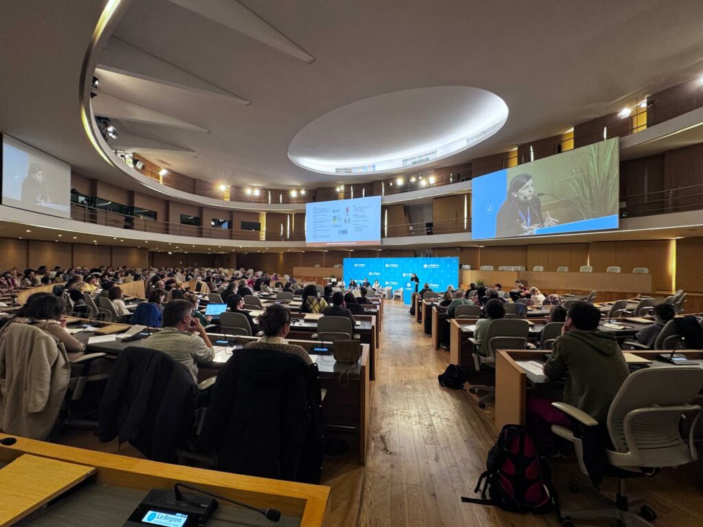 Photo prise dans l'hémicycle de l'Hôtel de région lors de la journée où l'on voit une personne en train d'intervenir sur un grand écran et le public de dos